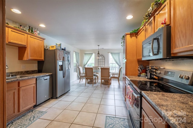 kitchen featuring hanging light fixtures, stainless steel appliances, sink, and light tile flooring