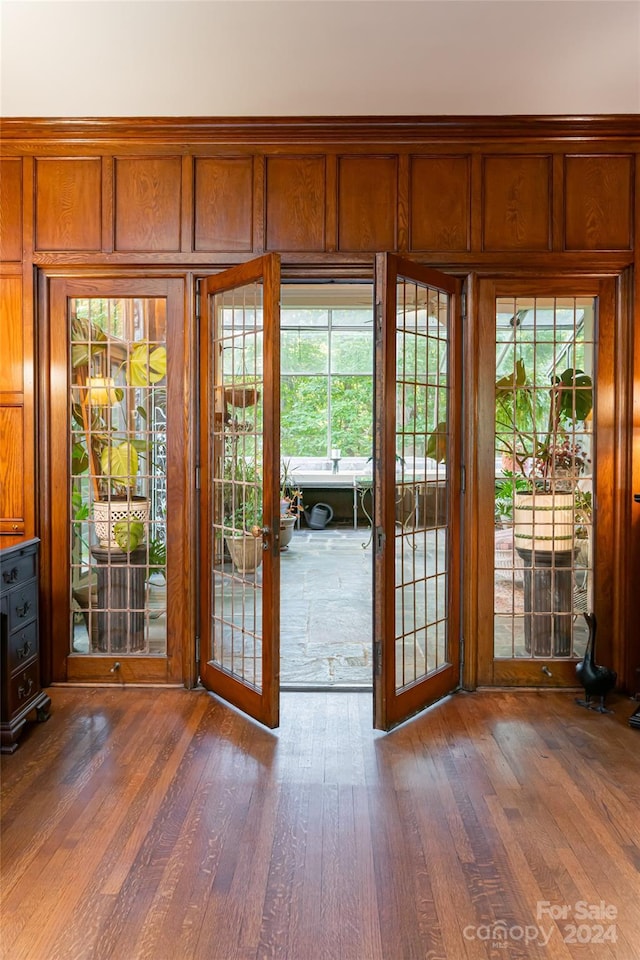 entryway with french doors, dark hardwood / wood-style flooring, and wooden walls