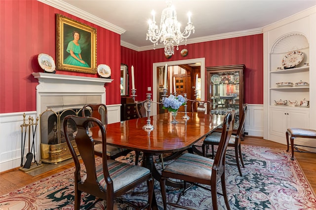 dining room with hardwood / wood-style floors, a chandelier, ornamental molding, a tile fireplace, and built in shelves