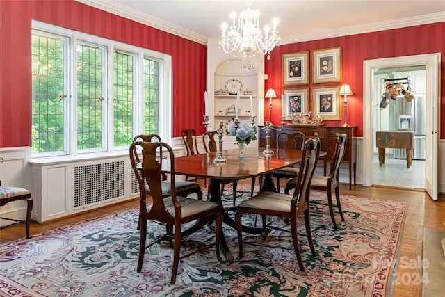 dining space with light hardwood / wood-style floors, radiator heating unit, ornamental molding, and a notable chandelier