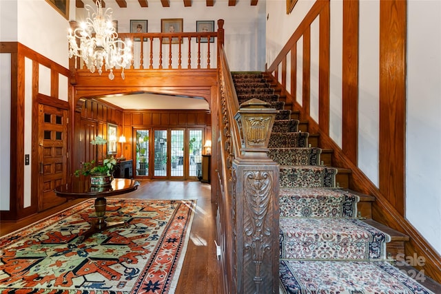 stairs with a chandelier, a towering ceiling, and hardwood / wood-style floors