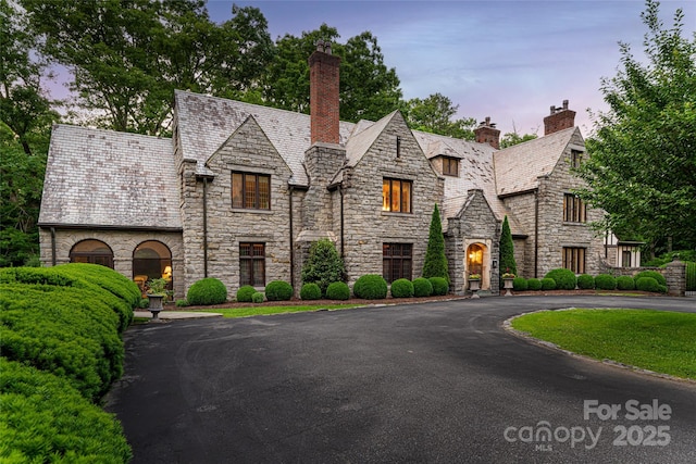 436 Vanderbilt Rd, Asheville, NC 28803 - tudor-style house featuring a high end roof, stone siding, a chimney, and driveway