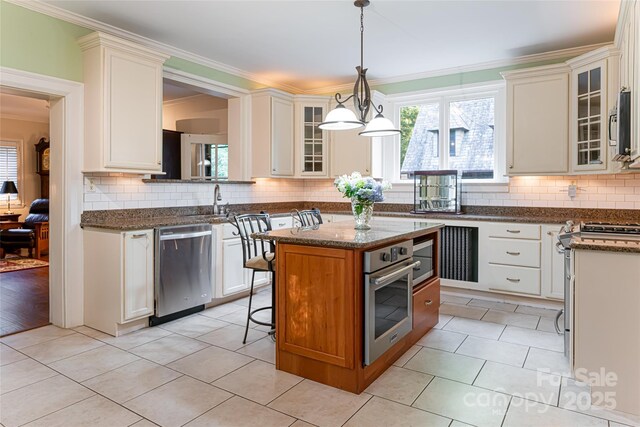 436 Vanderbilt Rd, Asheville, NC 28803 - kitchen with appliances with stainless steel finishes, ornamental molding, plenty of natural light, a center island, and glass insert cabinets