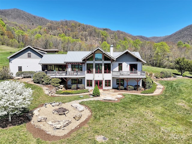 back of house with a yard and a deck with mountain view