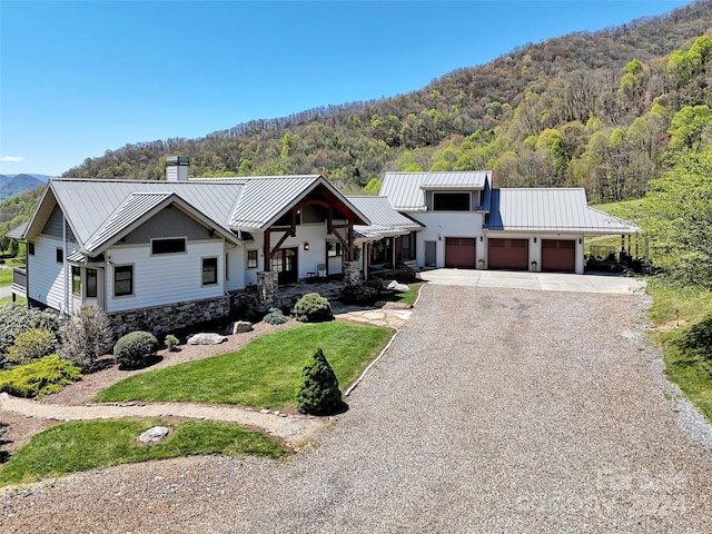 view of front facade with a front yard, a porch, a garage, and a mountain view