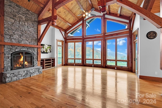 unfurnished living room featuring wooden ceiling, light hardwood / wood-style floors, and a stone fireplace