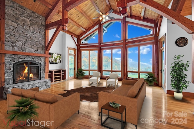 living room with light hardwood / wood-style flooring, high vaulted ceiling, wood ceiling, and a stone fireplace