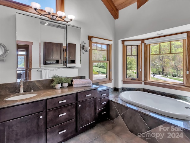 bathroom with vanity, tiled tub, an inviting chandelier, tile patterned flooring, and vaulted ceiling with beams