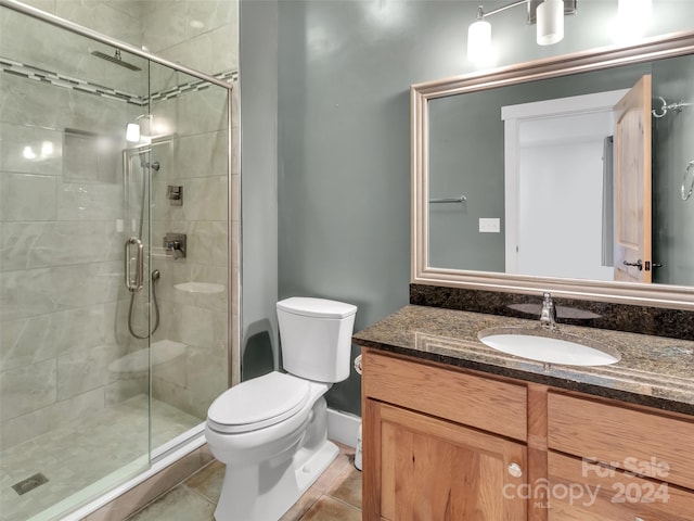 bathroom featuring toilet, vanity, tile patterned floors, and an enclosed shower