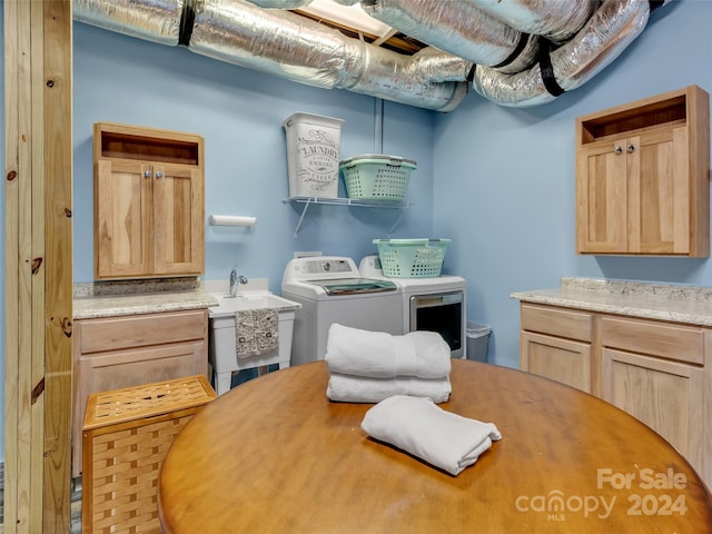 laundry room featuring washing machine and dryer, sink, and cabinets