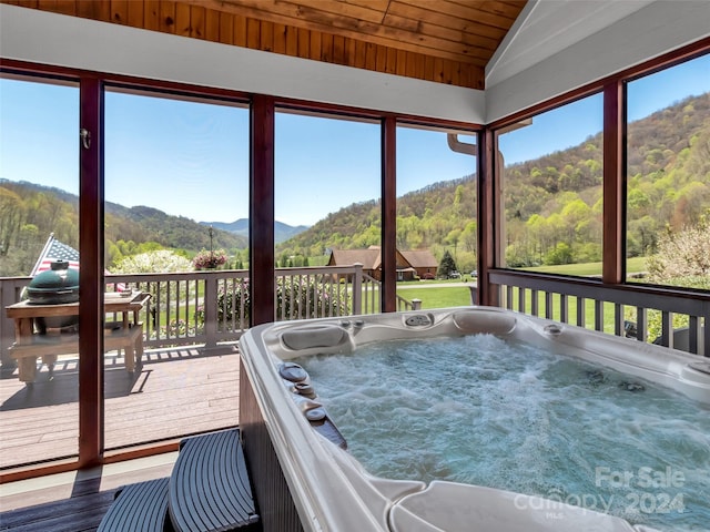 sunroom with wood ceiling, lofted ceiling, a mountain view, and a hot tub