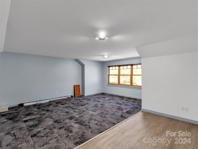 spare room featuring wood-type flooring and baseboard heating