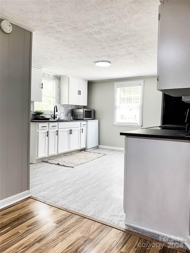 kitchen with white cabinets, light hardwood / wood-style floors, and a textured ceiling