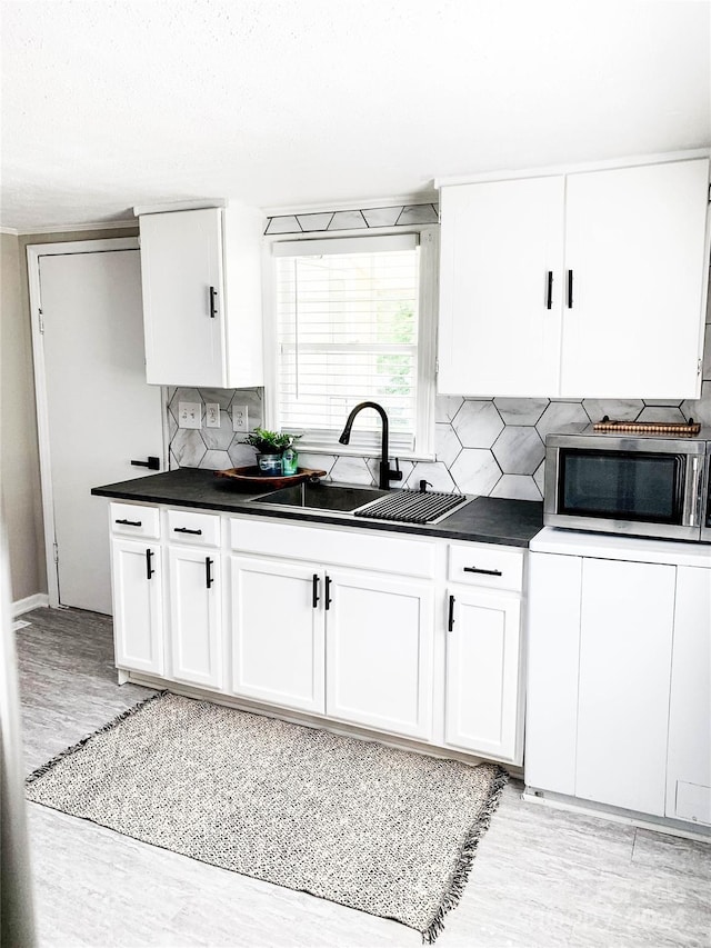 kitchen with white cabinets, sink, tasteful backsplash, and light wood-type flooring