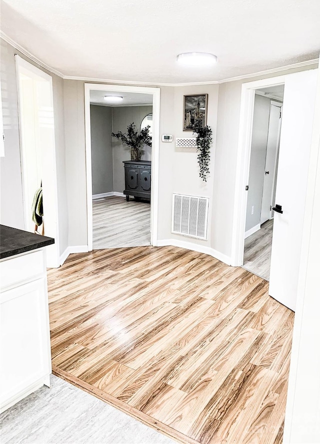 corridor featuring ornamental molding and light hardwood / wood-style flooring