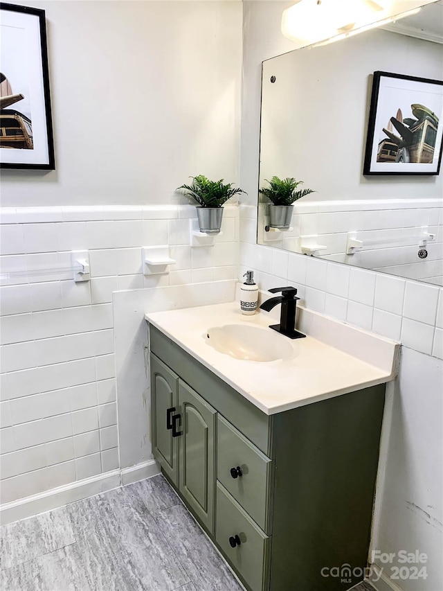 bathroom with vanity with extensive cabinet space, hardwood / wood-style floors, tile walls, and backsplash