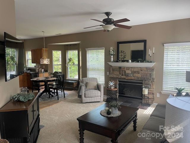 living room with light carpet, ceiling fan, and a stone fireplace