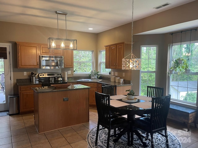 kitchen with a kitchen island, light tile patterned floors, hanging light fixtures, stainless steel appliances, and sink