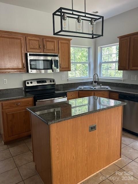 kitchen featuring a kitchen island, decorative light fixtures, appliances with stainless steel finishes, sink, and a wealth of natural light