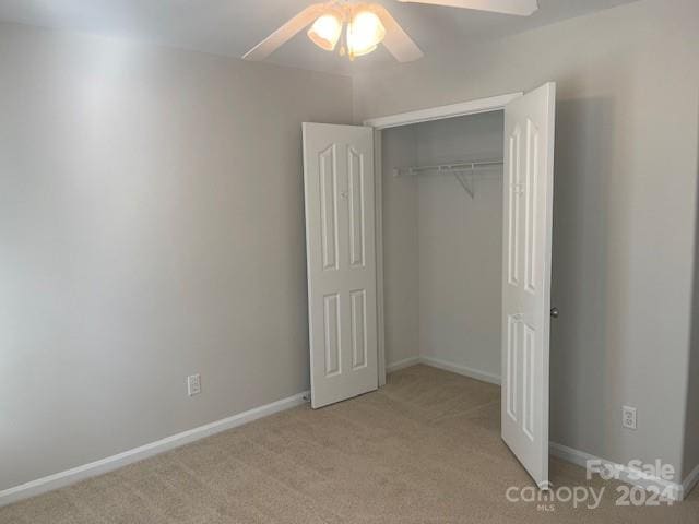 unfurnished bedroom featuring light colored carpet, ceiling fan, and a closet