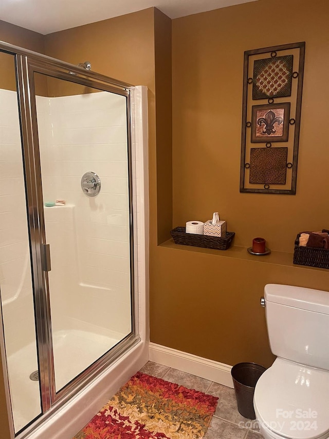 bathroom featuring tile patterned flooring, toilet, and walk in shower