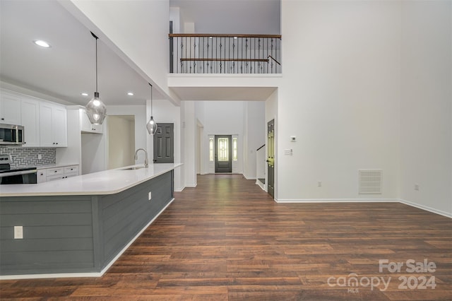 kitchen featuring backsplash, electric range oven, dark wood-type flooring, sink, and pendant lighting