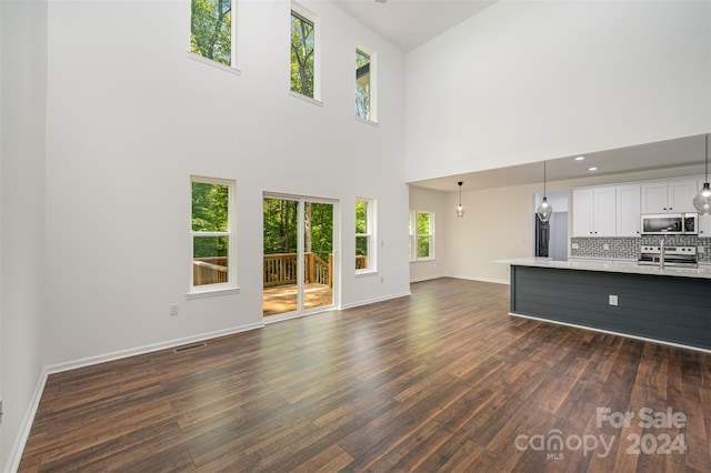 unfurnished living room with dark hardwood / wood-style flooring and a high ceiling