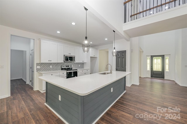 kitchen featuring sink, appliances with stainless steel finishes, a kitchen island with sink, and dark wood-type flooring