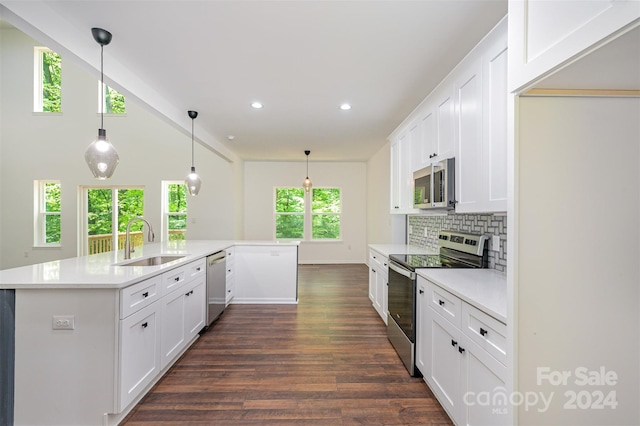 kitchen with decorative light fixtures, appliances with stainless steel finishes, dark wood-type flooring, white cabinetry, and sink