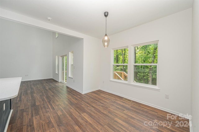 spare room with a healthy amount of sunlight and dark wood-type flooring