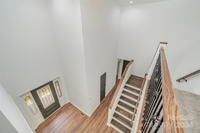 stairway with dark hardwood / wood-style floors and a high ceiling