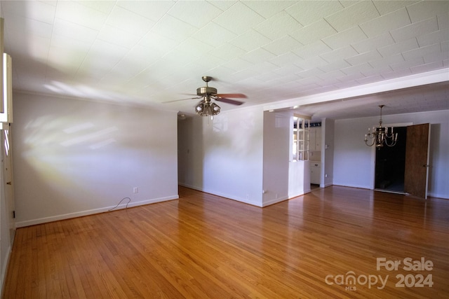 empty room with ceiling fan with notable chandelier and hardwood / wood-style flooring