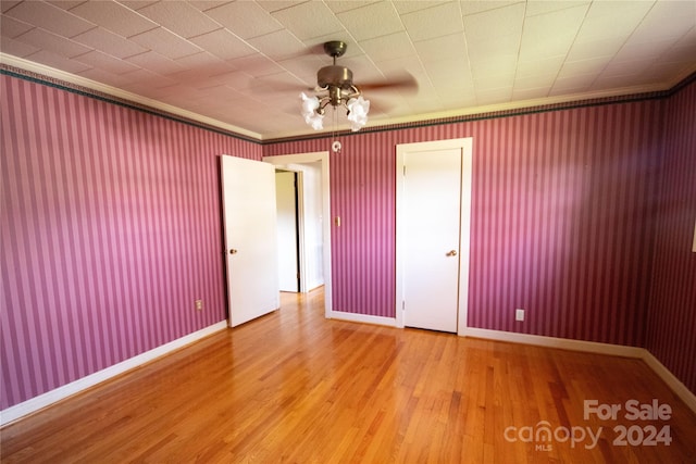 unfurnished bedroom featuring hardwood / wood-style floors, ceiling fan, and crown molding