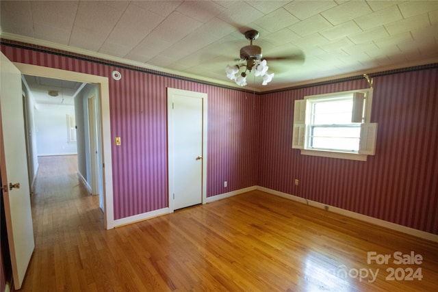 spare room featuring ceiling fan, hardwood / wood-style flooring, and crown molding