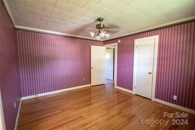 empty room featuring wood-type flooring, ceiling fan, and crown molding