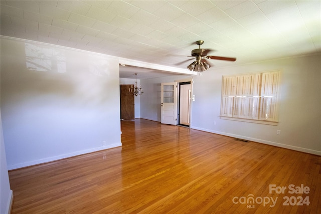 unfurnished room featuring hardwood / wood-style floors, ornamental molding, and ceiling fan with notable chandelier