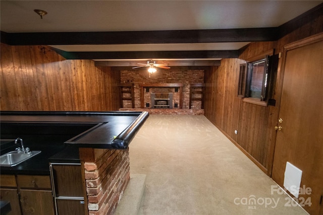 playroom featuring ceiling fan, beam ceiling, a brick fireplace, wooden walls, and sink