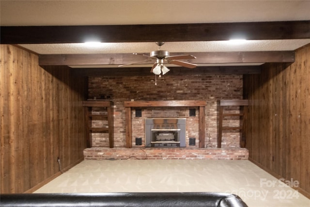 unfurnished living room with beamed ceiling, wooden walls, and a brick fireplace