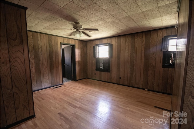 unfurnished room featuring wooden walls, ceiling fan, and hardwood / wood-style flooring