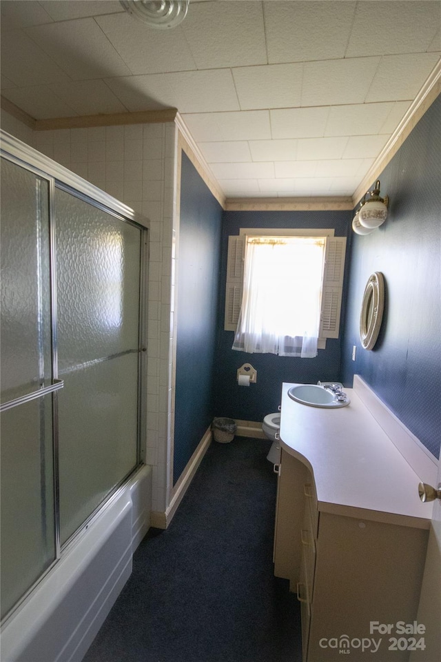 full bathroom with crown molding, bath / shower combo with glass door, vanity, and toilet