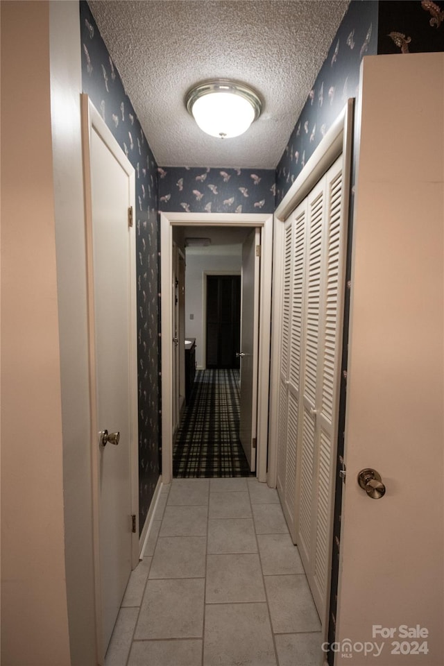 hall featuring light tile floors and a textured ceiling