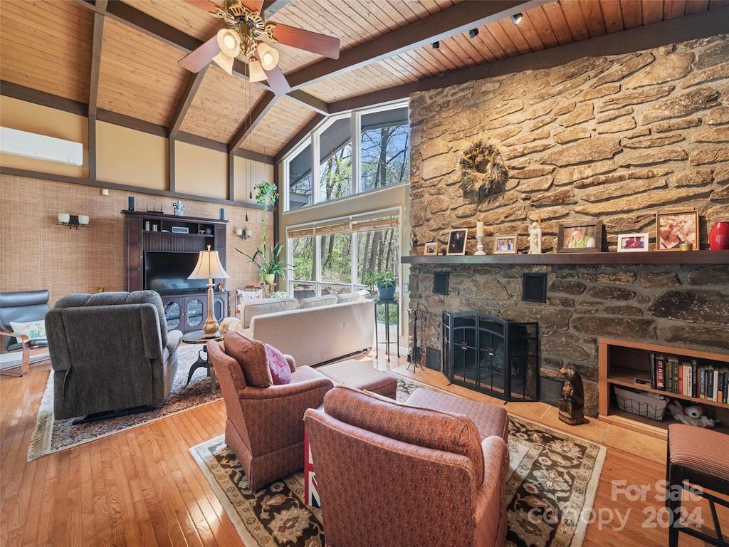 living room with hardwood / wood-style flooring, ceiling fan, beam ceiling, a stone fireplace, and wooden ceiling