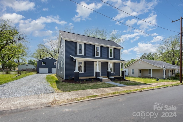 view of front of property featuring a garage, a porch, an outdoor structure, and a front yard