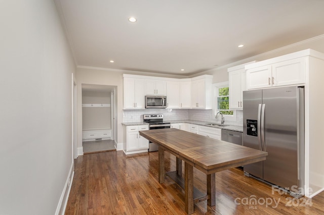 kitchen with white cabinets, appliances with stainless steel finishes, crown molding, and dark hardwood / wood-style floors