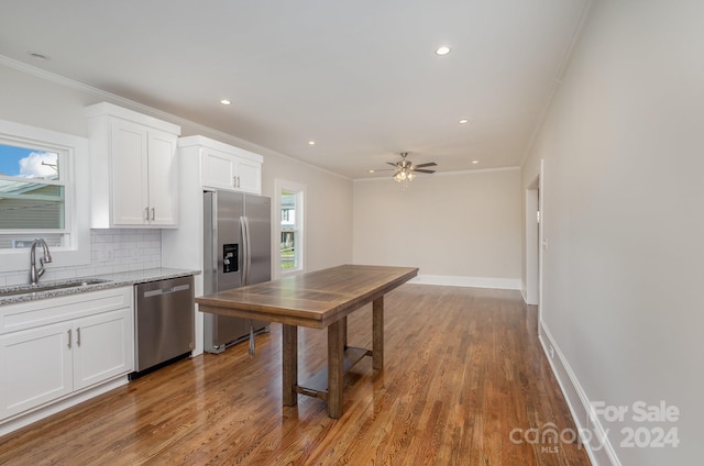 kitchen with white cabinets, hardwood / wood-style floors, stainless steel appliances, sink, and ceiling fan