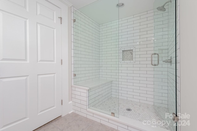 bathroom with an enclosed shower and tile flooring