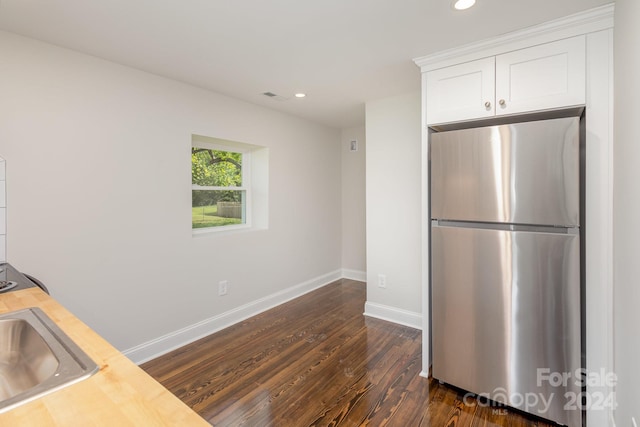 kitchen with sink, white cabinetry, dark wood-type flooring, stainless steel fridge, and butcher block counters