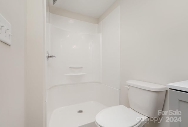 bathroom with a shower, vanity, and toilet