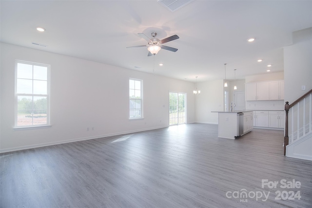 unfurnished living room featuring ceiling fan, wood-type flooring, sink, and a healthy amount of sunlight