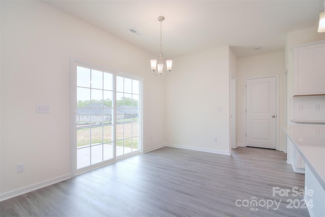 unfurnished dining area featuring light hardwood / wood-style flooring and an inviting chandelier